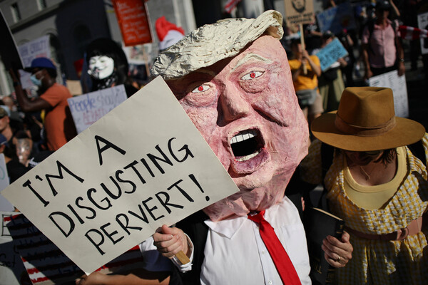 18일, 미국 캘리포니아주 로스앤젤레스 시청 앞에서 도널드 트럼프 미국 대통령의 정책에 항의하는 시위 중, 트럼프 마스크를 쓴 시위자가 