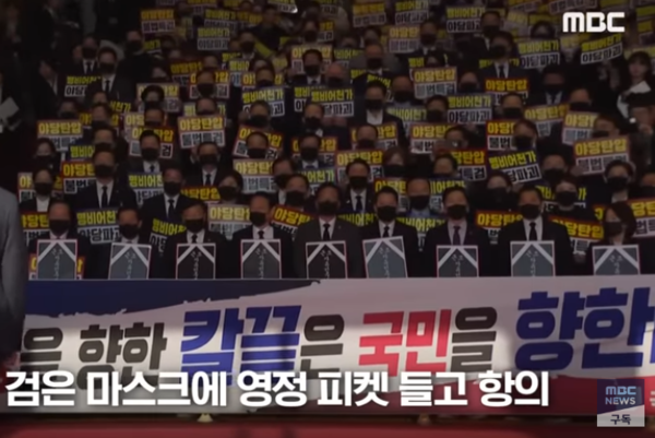 4일 국민의힘 소속 의원들이 이재명 대통령의 시정연설 불참을 선언하고 본회장 앞에서 검은 마스크에 영정사진을 든 채 이재명 대통령을 향해 항의하는 모습. MBC뉴스 유튜브 화면 캡쳐. 